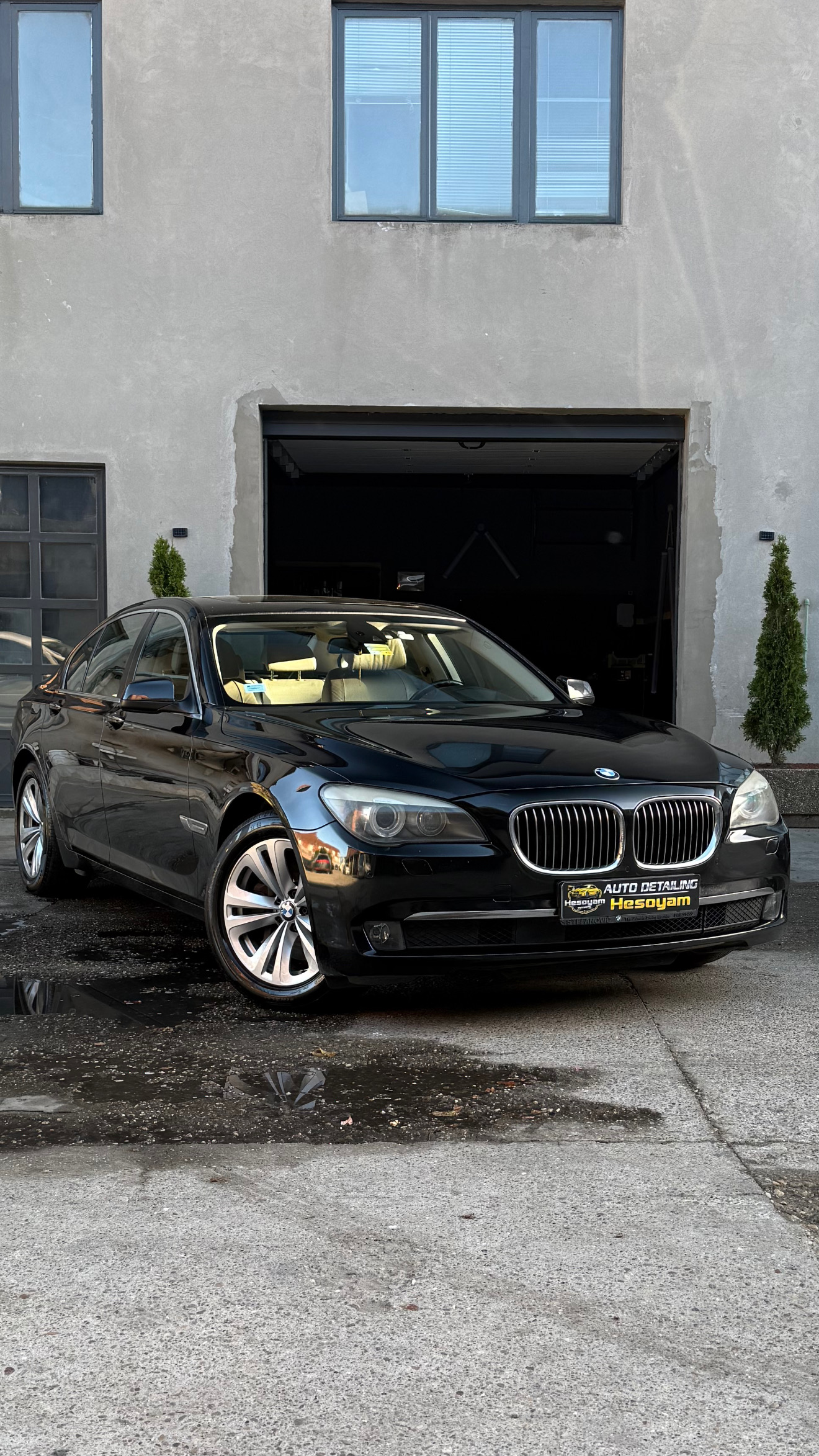 Crna BMW Serija 7 sa savršenim sjajnim lakom ispred garaže